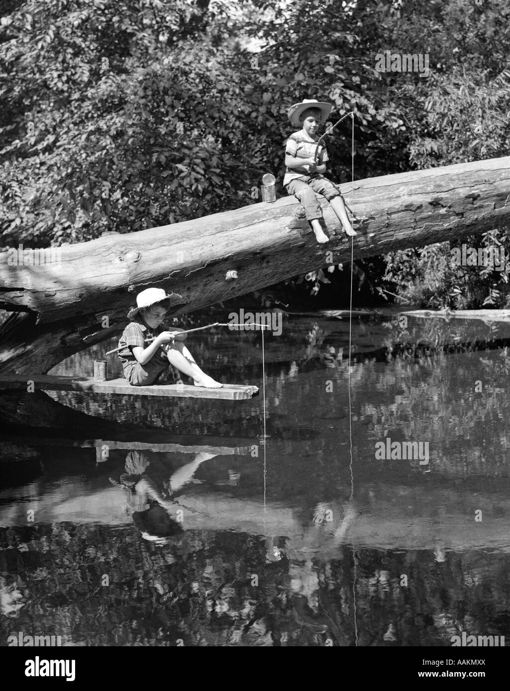 1940s 1950s PAIR OF BOYS IN STRAW HATS & CUFFED JEANS FISHING IN STREAM OFF  OF FALLEN TREE WITH STICK & STRING POLES Stock Photo - Alamy