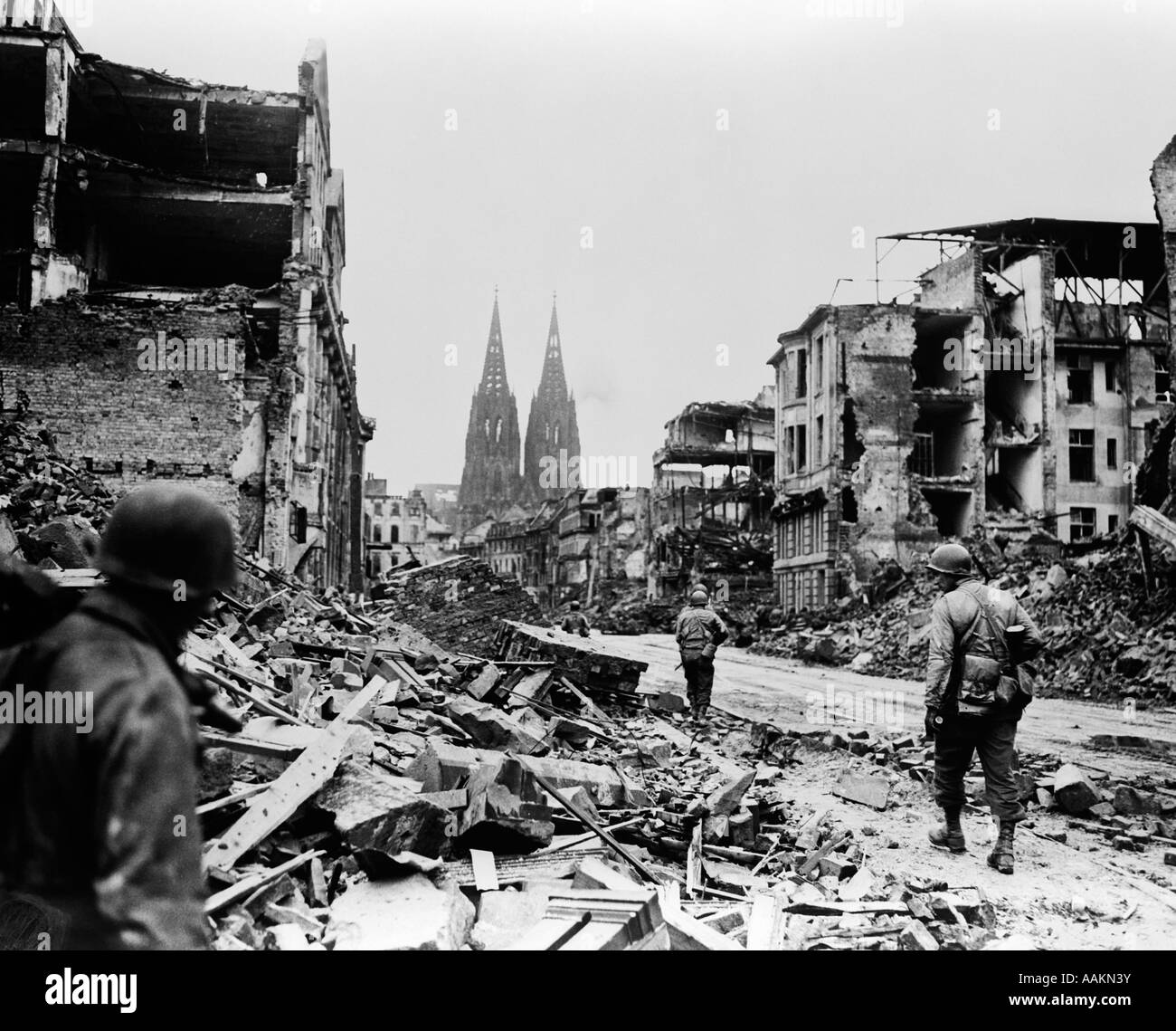 1940s AMERICAN SOLDIERS WALKING IN RUINS OF COLOGNE GERMANY Stock Photo