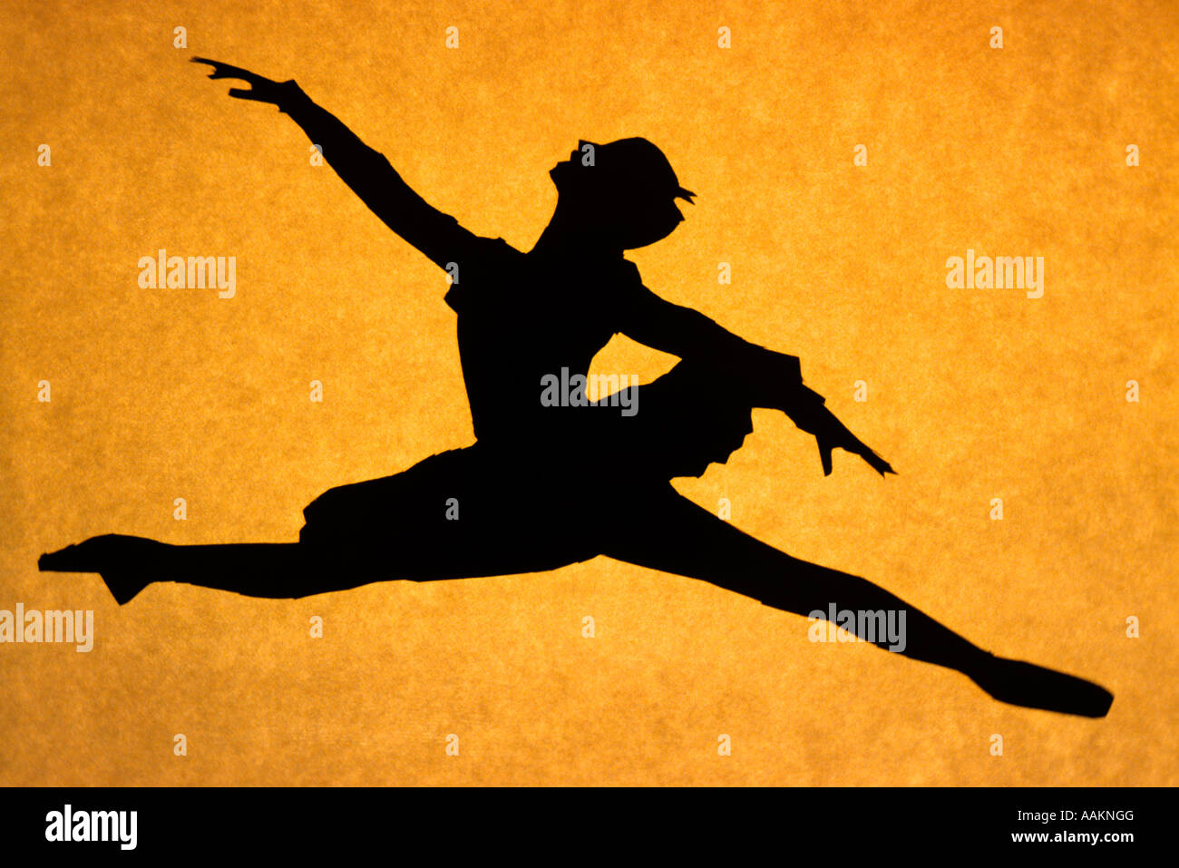 SILHOUETTED BALLERINA JUMPING A GRAND JETE AGAINST ORANGE BACKGROUND Stock Photo