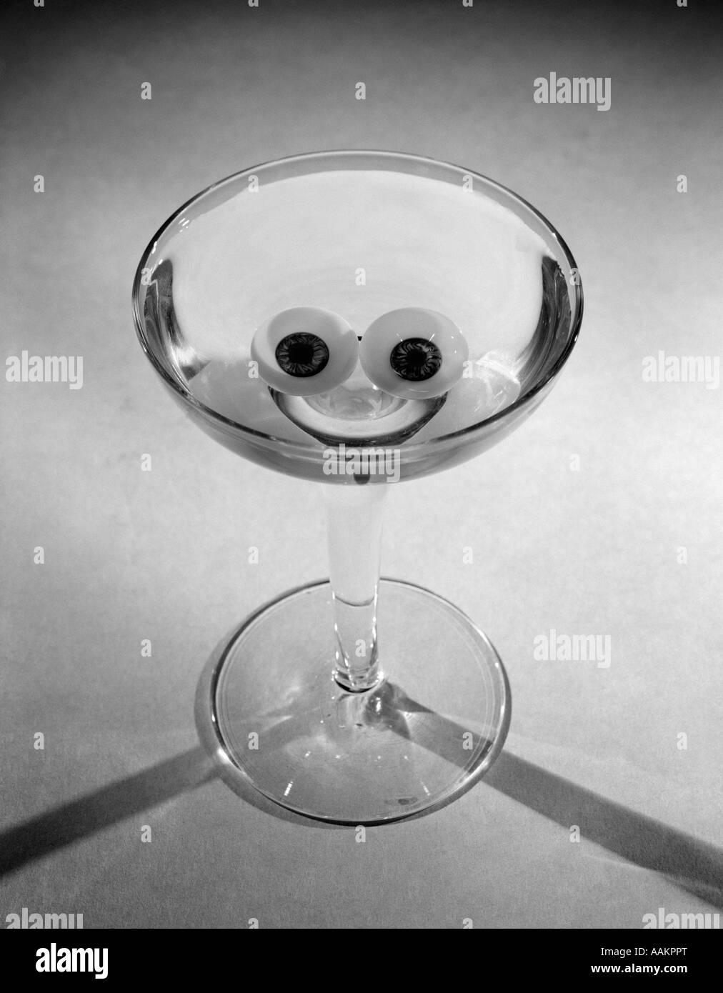1950s MARTINI GLASS WITH OLIVES & RIND LEMON POSITIONED TO LOOK LIKE A SMILEY FACE HAPPY HOUR Stock Photo