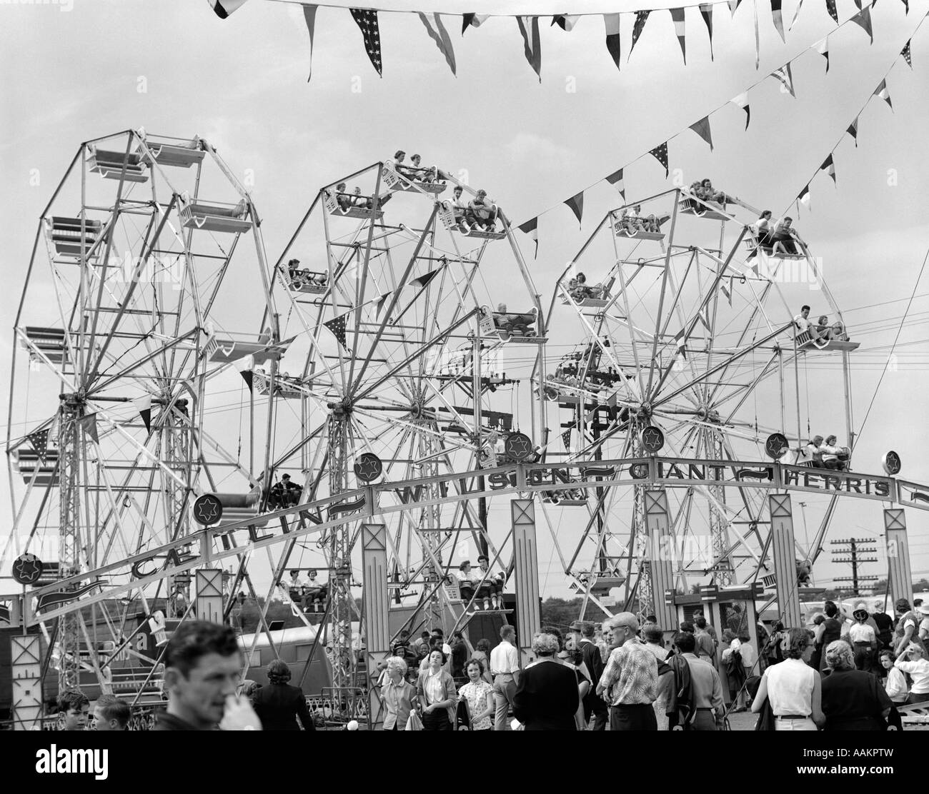 1950s FAIR SCENE SHOWING 3 GIANT FERRIS WHEELS & CROWD BELOW Stock Photo