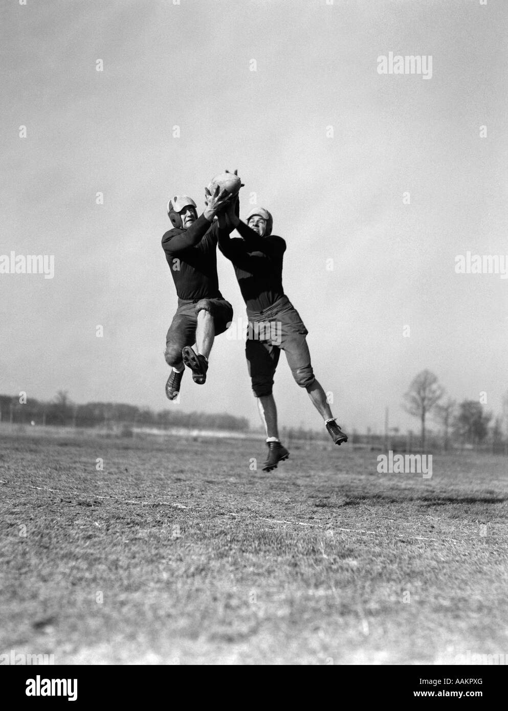 1930s TWO FOOTBALL PLAYERS JUMPING TO CATCH BALL PASS INTERCEPTION ...