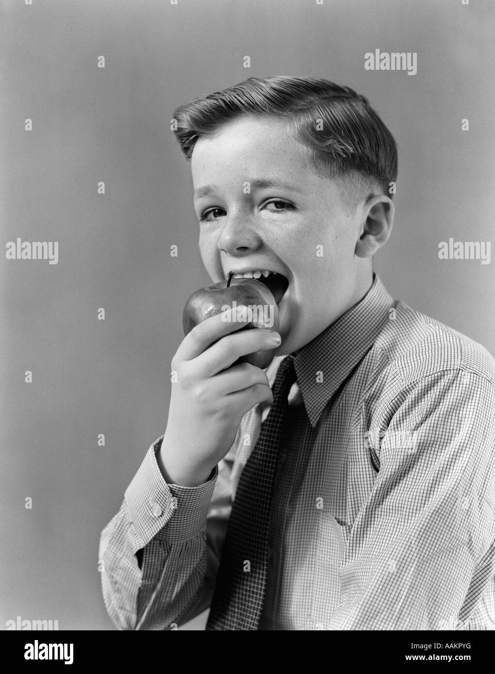 1940s BOY EATING BITING INTO APPLE LOOKING AT CAMERA Stock Photo