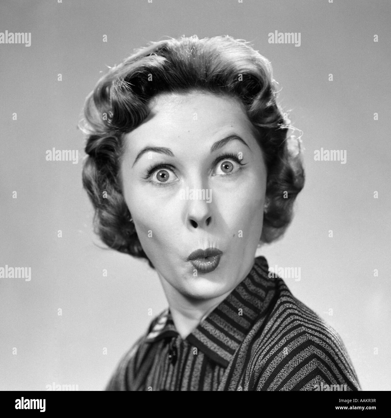 1950s WOMAN MAKING FUNNY FACE EYES WIDE LIPS PURSED AS IN A KISS OR A WHISTLE LOOKING AT CAMERA Stock Photo