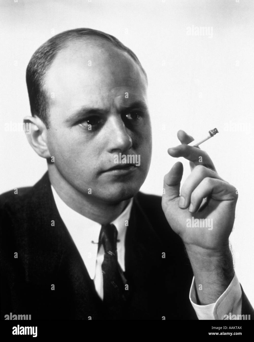 1960s PORTRAIT OF MAN SMOKING HOLDING A CIGARETTE Stock Photo