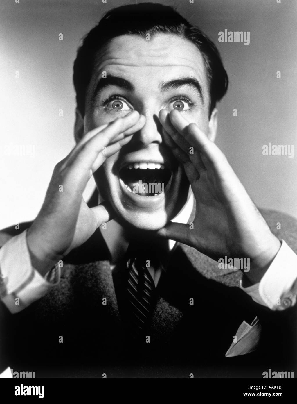 1940s 1950s EXCITED MAN WITH HANDS CUPPED AROUND MOUTH SHOUTING Stock Photo