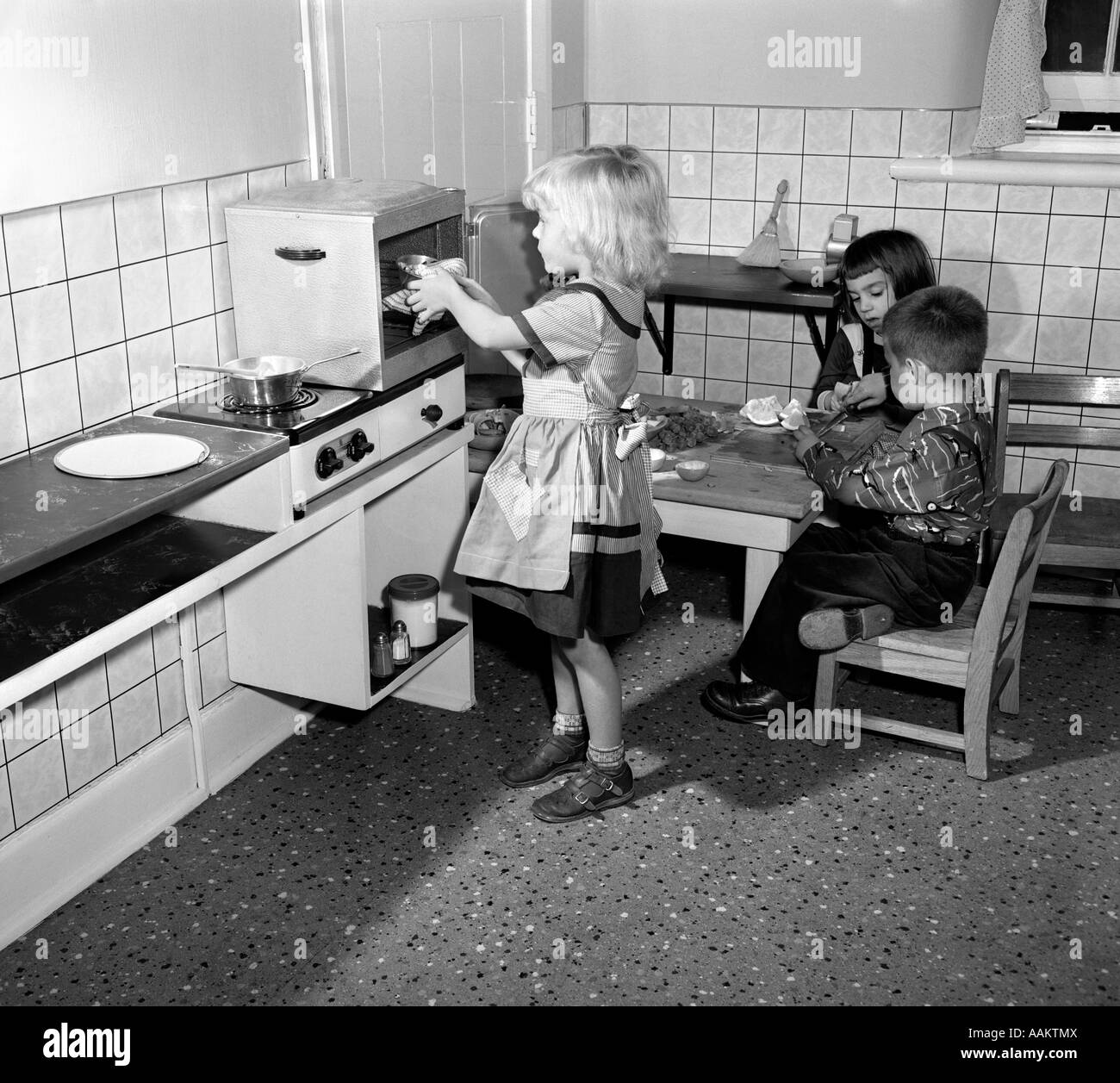 1950s CHILDREN BOYS GIRLS NURSERY SCHOOL IN TOY PLAY KITCHEN Stock Photo
