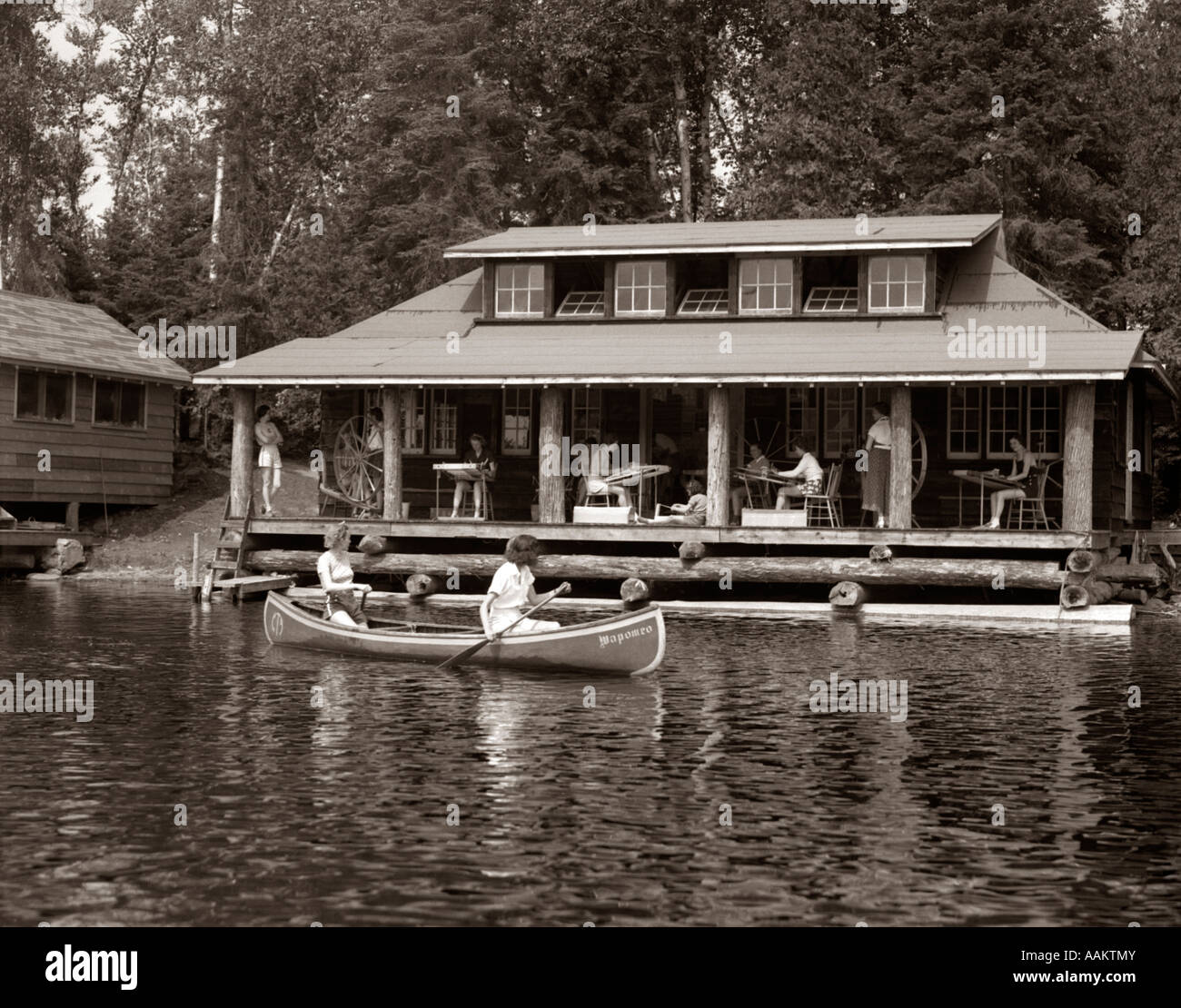 1950s Two Women Paddling Canoe By Cabin In Lake Algonquin Park