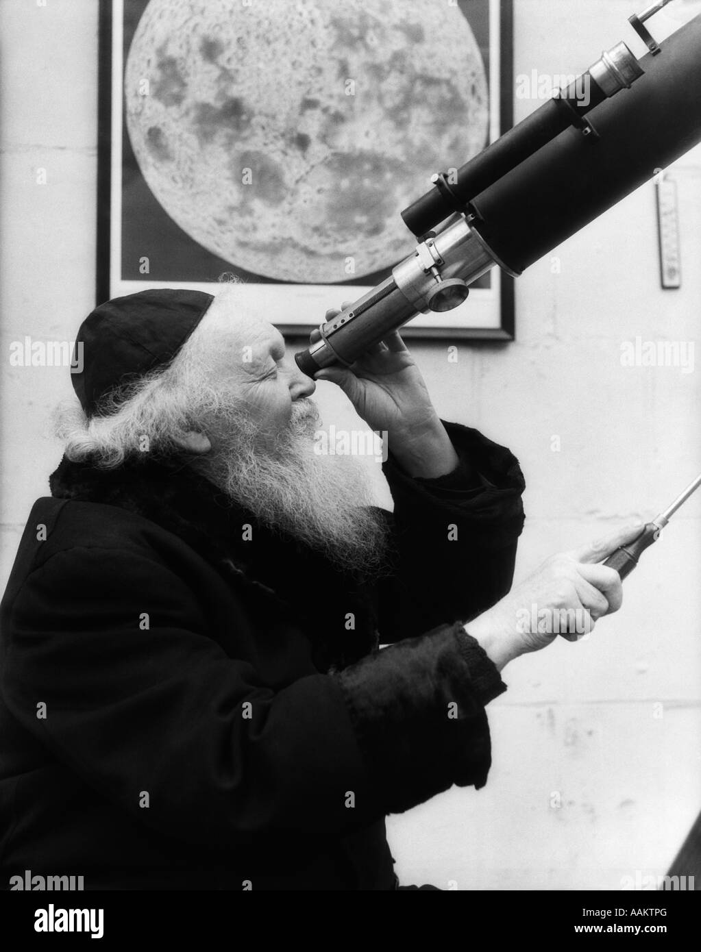 1930s OLD ASTRONOMER WHITE HAIR AND BEARD WEARING SKULL CAP LOOKING THROUGH TELESCOPE Stock Photo