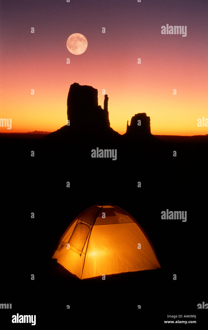 1990s ILLUMINATED TENT AT NIGHT UNDER FULL MOON IN MONUMENT VALLEY Stock Photo