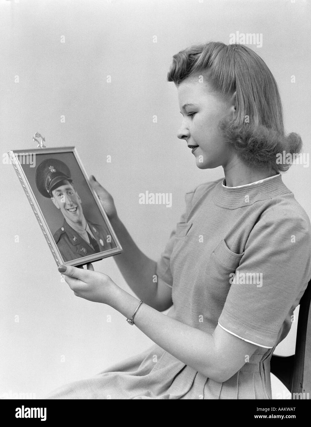 1940s YOUNG WOMAN TEEN GIRL HOLDING FRAMED PHOTO OF MAN IN MILITARY UNIFORM Stock Photo