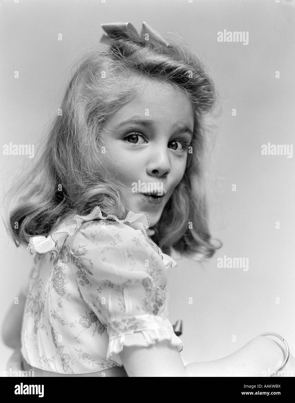 1940s PORTRAIT YOUNG GIRL TURNED TO ONE SIDE LOOKING AT CAMERA WITH FUNNY FACIAL EXPRESSION Stock Photo