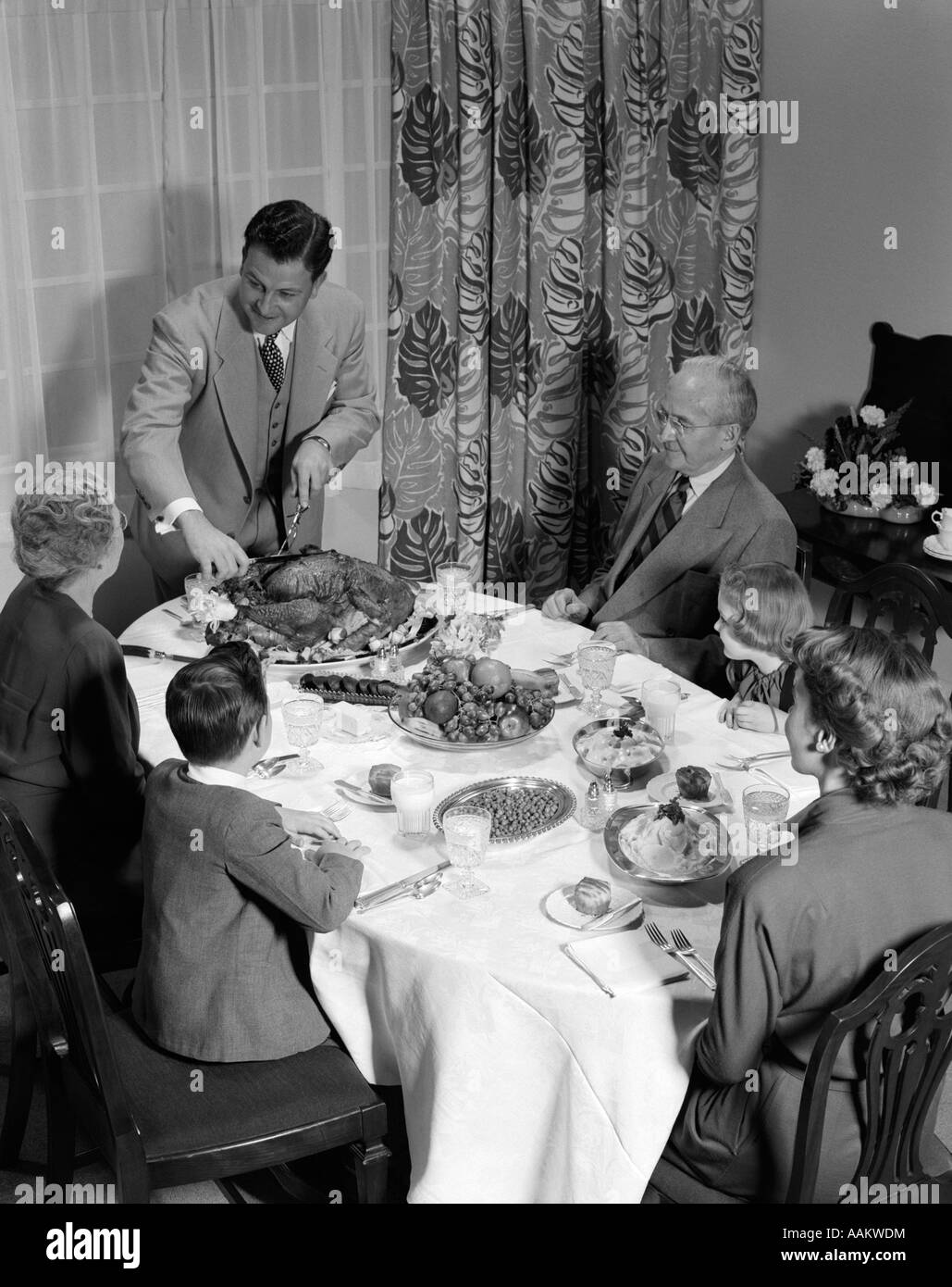 1950s 3 GENERATIONS THANKSGIVING DINNER WITH FATHER CARVING TURKEY Stock Photo