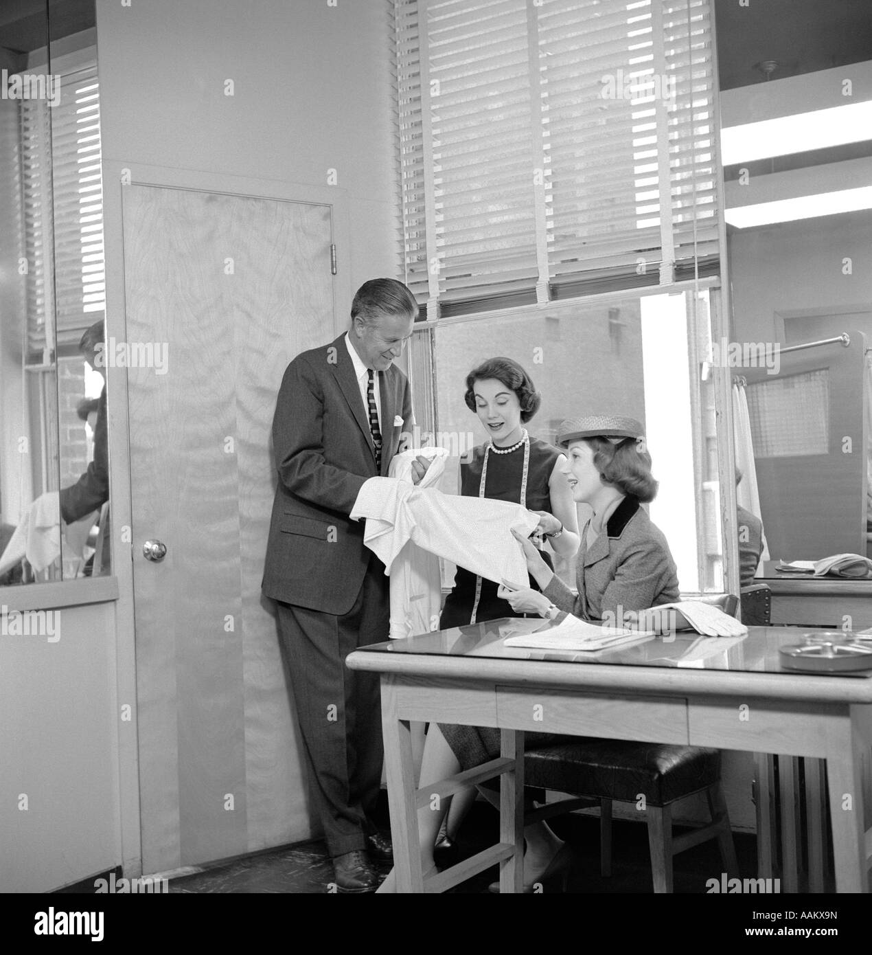 1950s FEMALE FASHION BUYER SELECTING FABRIC IN GARMENT INDUSTRY SHOWROOM Stock Photo