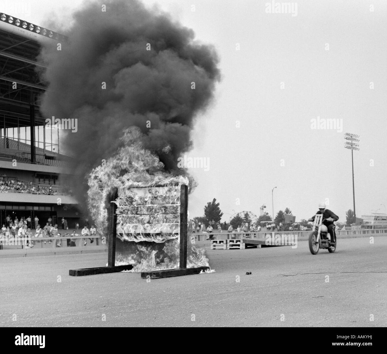 1960s DAREDEVIL ON MOTORCYCLE APPROACHING WALL OF FIRE Stock Photo