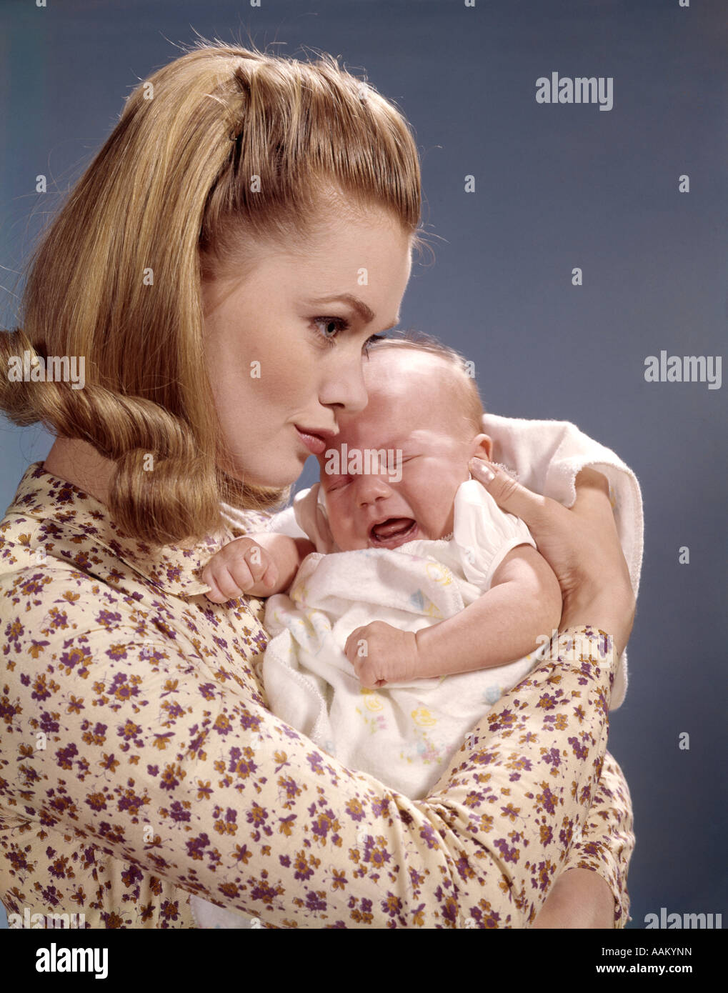 1960s CLOSE-UP OF MOTHER HOLDING CRYING BABY INFANT WOMAN FUSSING PROFILE CUDDLING Stock Photo