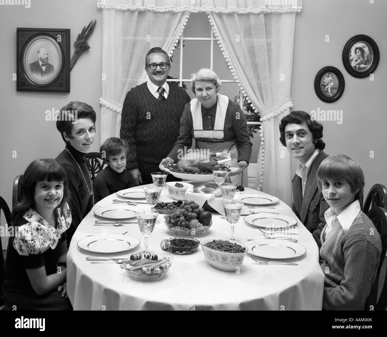 1970s 3 GENERATION FAMILY SITTING DINING ROOM TABLE GRANDMOTHER SETTING DOWN TURKEY PLATTER Stock Photo