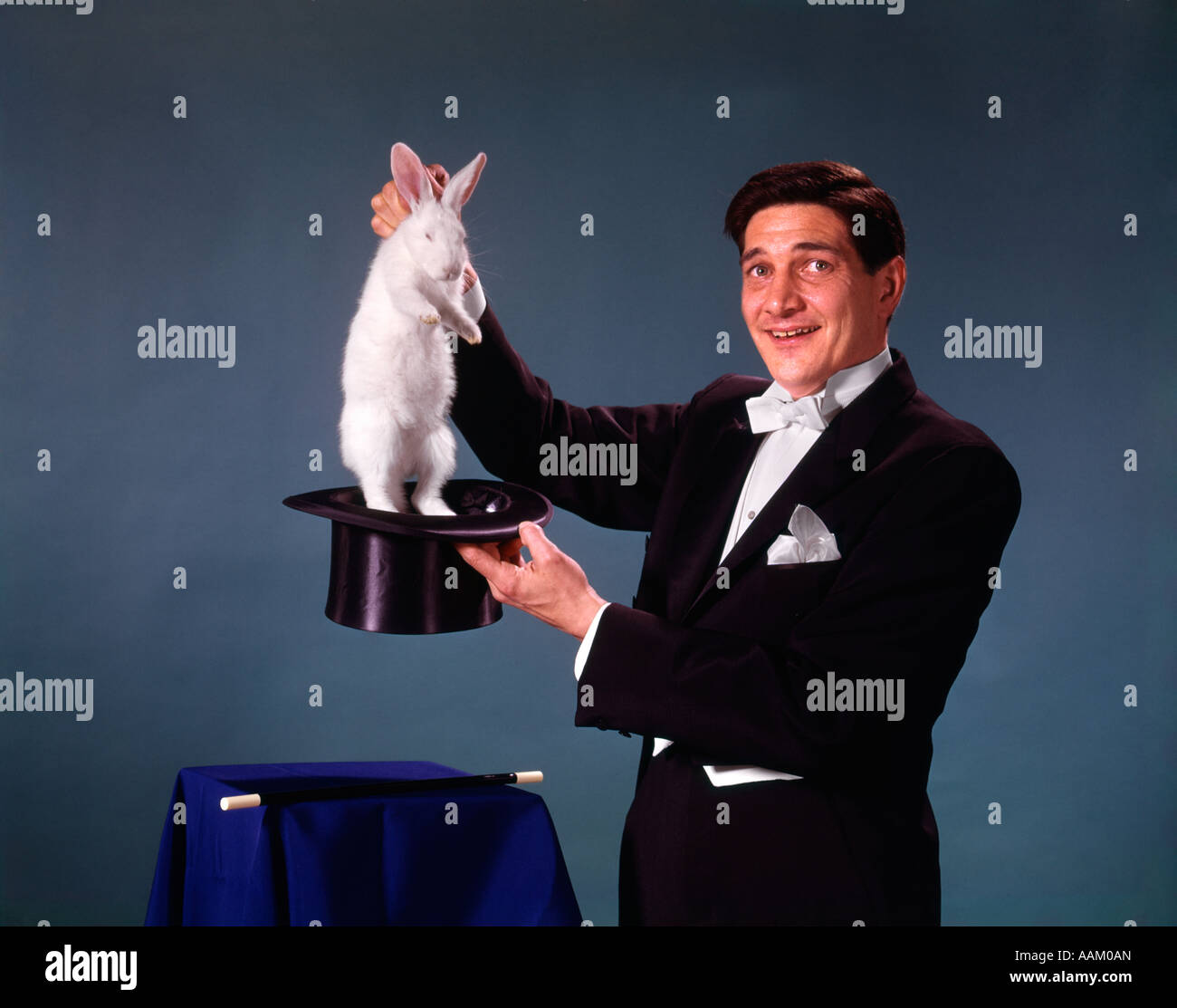1960s 1970s MAN MAGICIAN TUXEDO PULLING RABBIT OUT OF TOP HAT MAGIC ILLUSION SLEIGHT OF HAND TRICK Stock Photo