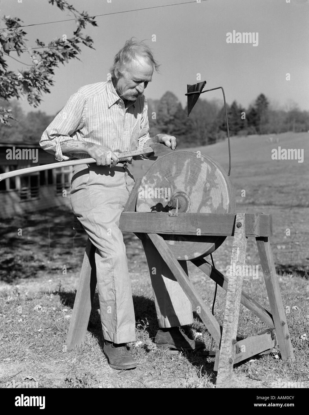 1940s ELDERLY MAN SEATED AT GRINDSTONE OUTDOORS SHARPEN TOOL AXE SHARP