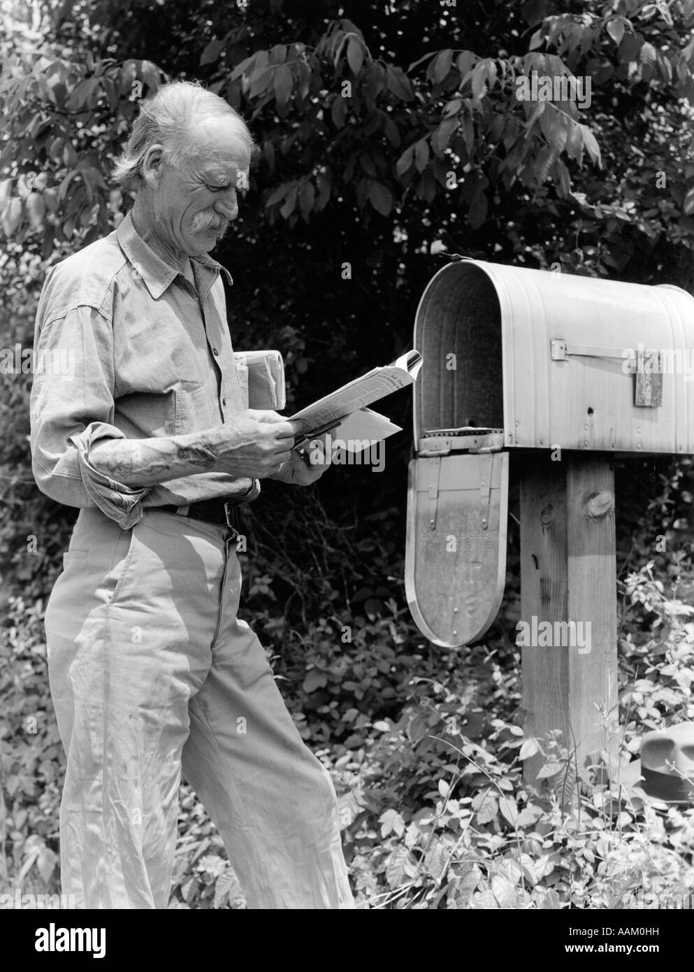 1940s SENIOR FARMER READING MAIL AT RURAL FREE DELIVERY MAIL BOX Stock