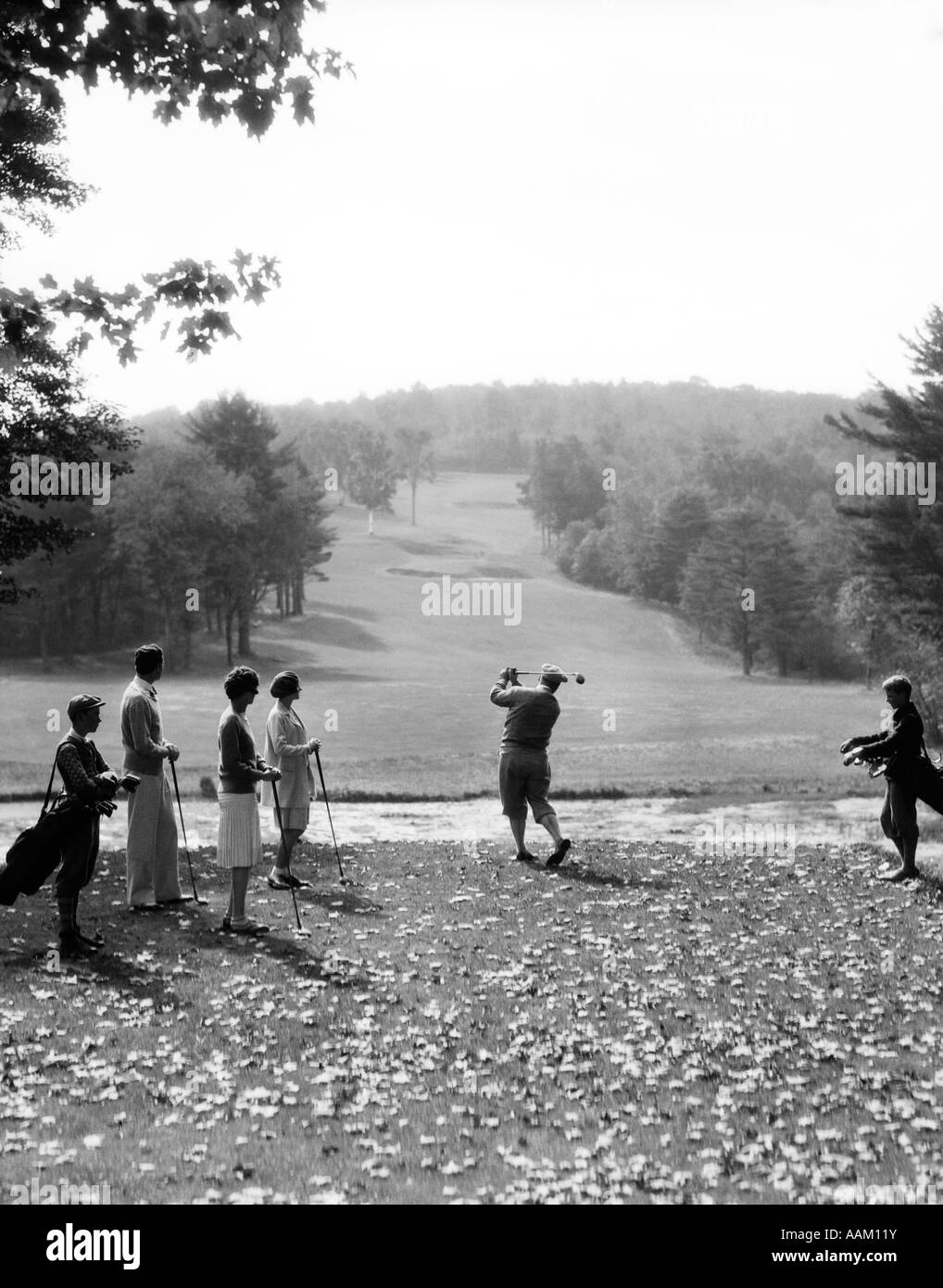 1920s 1930s GROUP OF GOLFERS TEEING OFF 2 MEN 2 WOMEN AND 2 CADDIES AT THE COUNTRY CLUB PITTSFIELD BERKSHIRES MA Stock Photo
