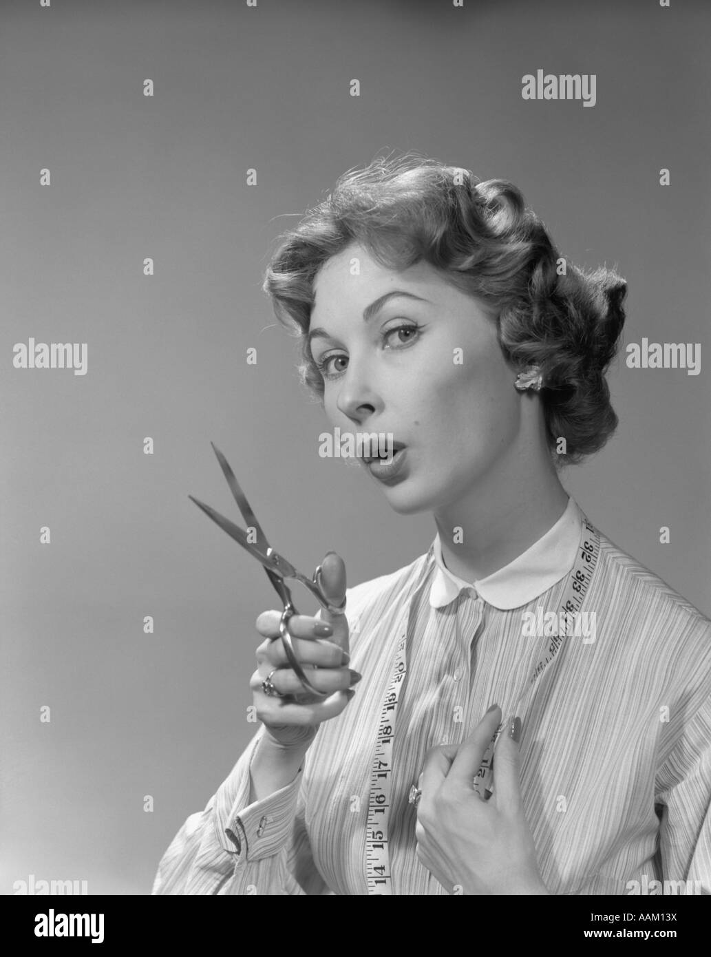 1950s 1960s PORTRAIT WOMAN HOLDING SCISSORS AND MEASURING TAPE LOOKING AT CAMERA Stock Photo