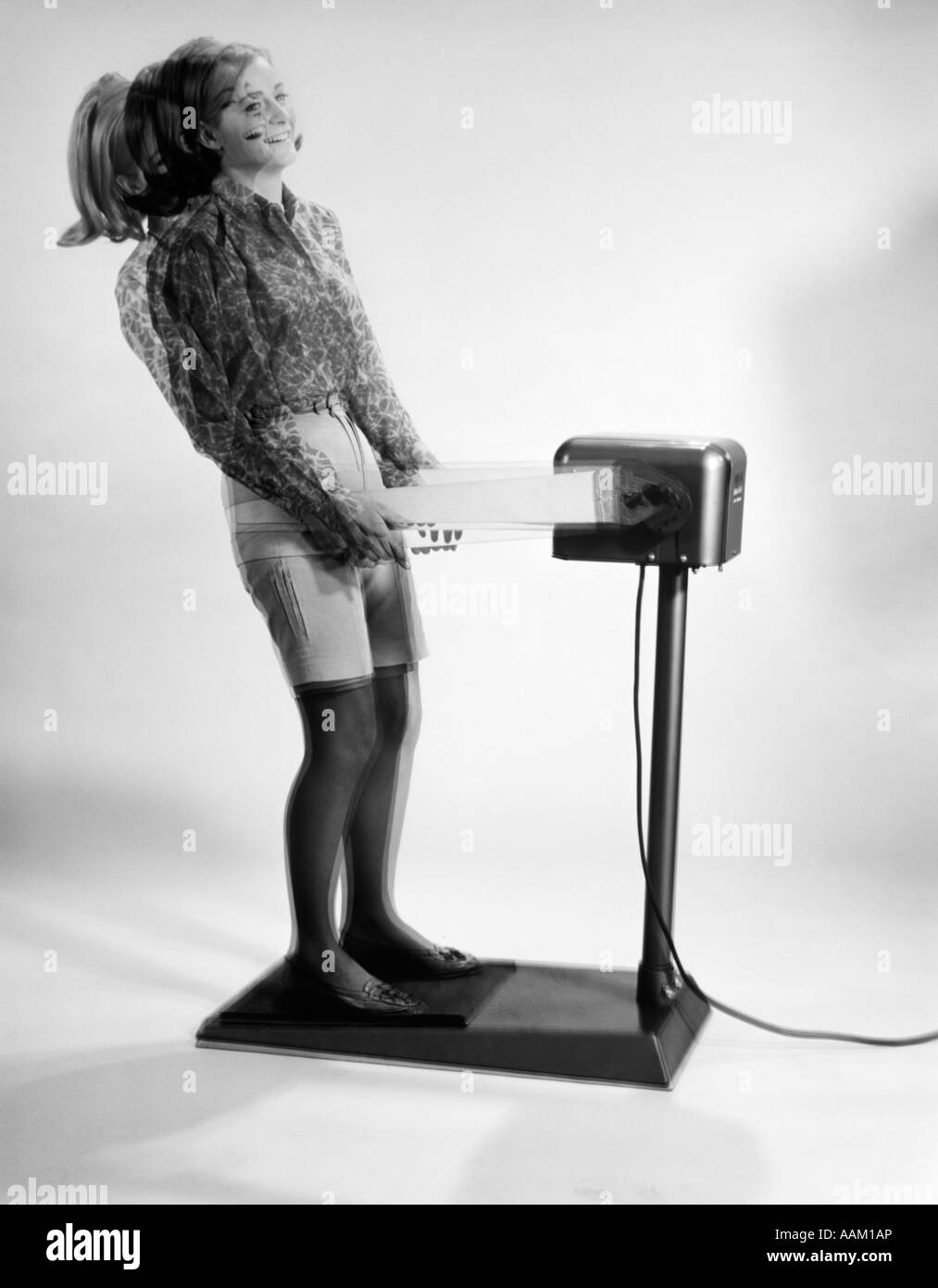 1960s WOMAN MASSAGED BY VIBRATING EXERCISE MACHINE Stock Photo