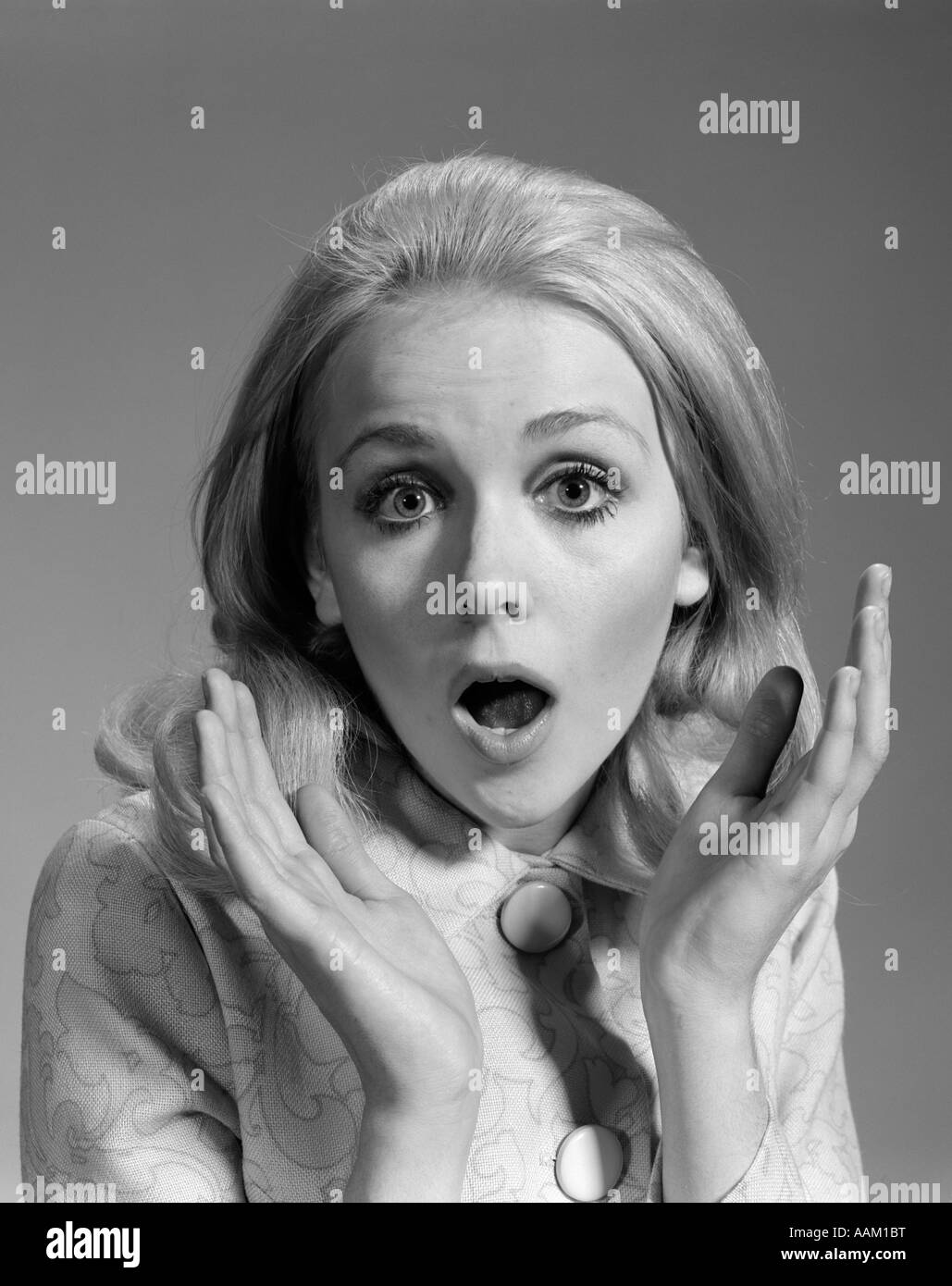 1960s BLOND WOMAN HANDS UP FRAMING FACE EXPRESSION OF SURPRISE AWE SHOCK LOOKING AT CAMERA Stock Photo