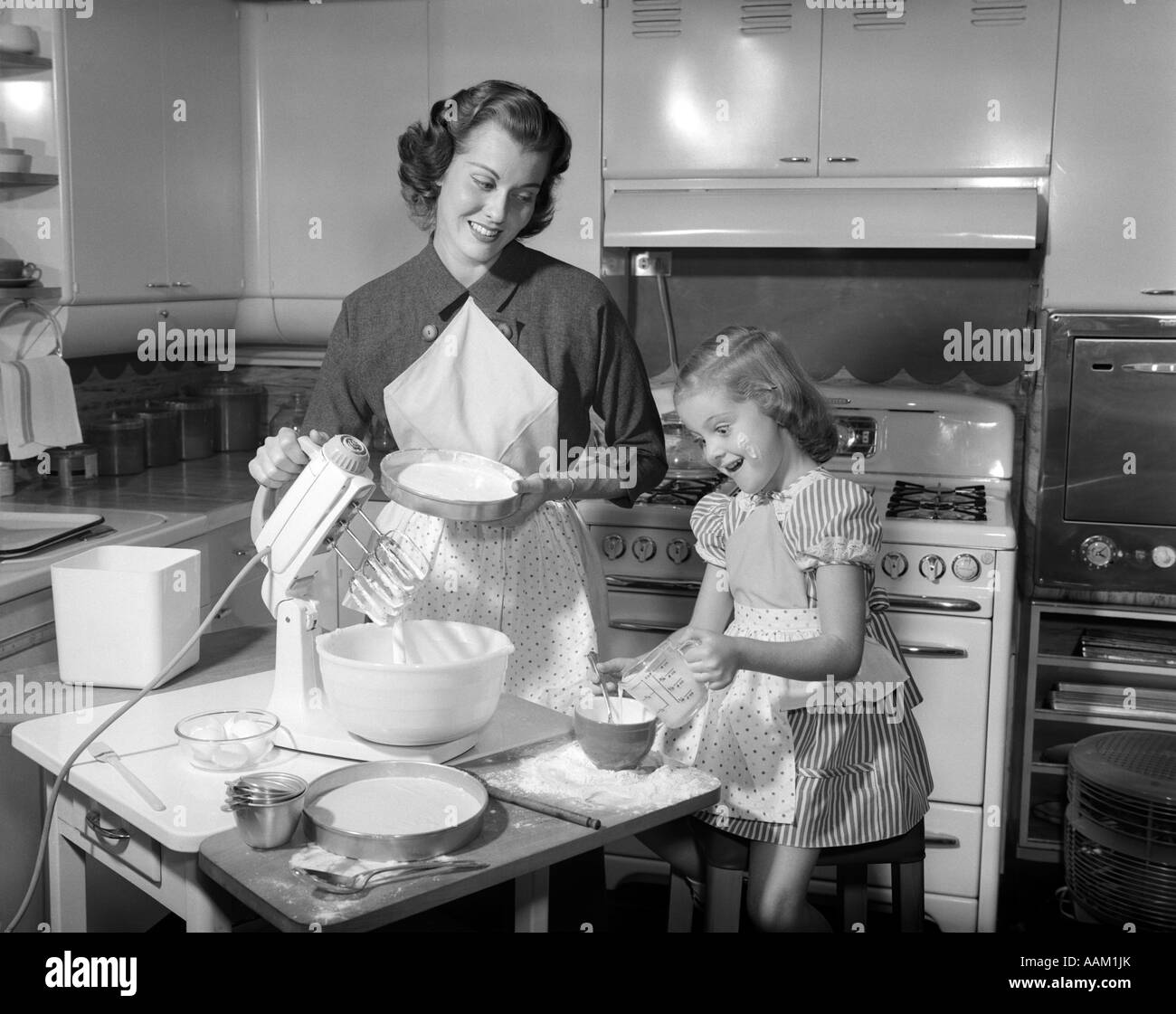 1950s MOTHER & DAUGHTER BAKING A CAKE Stock Photo