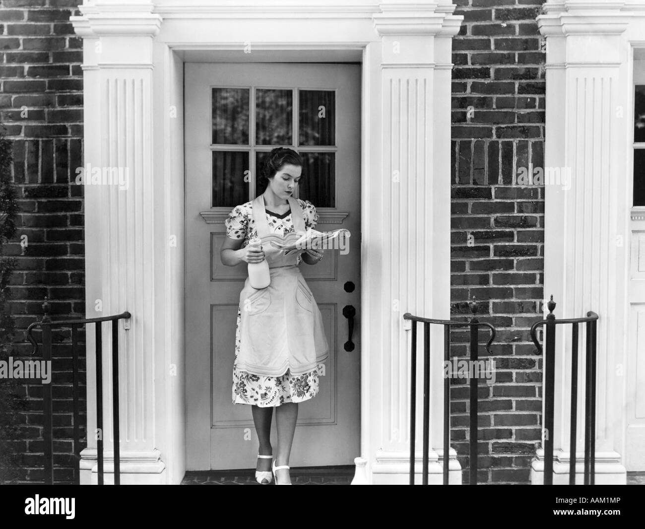 1940s WOMAN IN AN APRON STANDING OUTSIDE DOORWAY HOLDING A QUART OF MILK  AND READING NEWSPAPER Stock Photo - Alamy