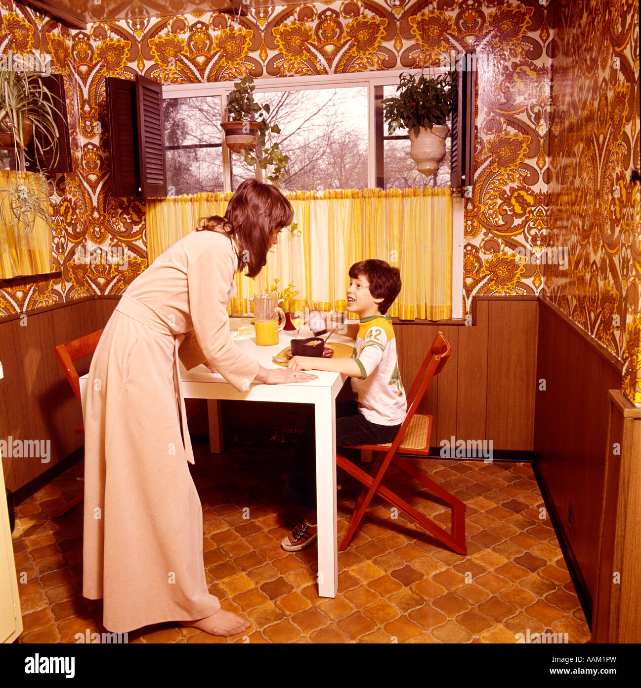 1970s MOTHER TALKING TO BOY CHILD EATING BREAKFAST CEREAL Stock Photo