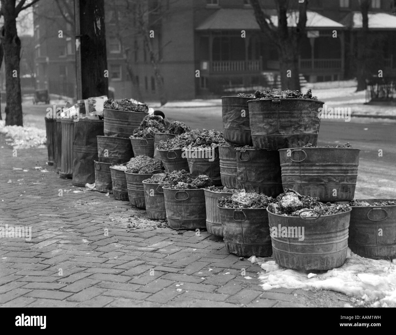 https://c8.alamy.com/comp/AAM1WH/1920s-1930a-coal-furnace-ash-cans-lined-up-on-brick-sidewalk-winter-AAM1WH.jpg