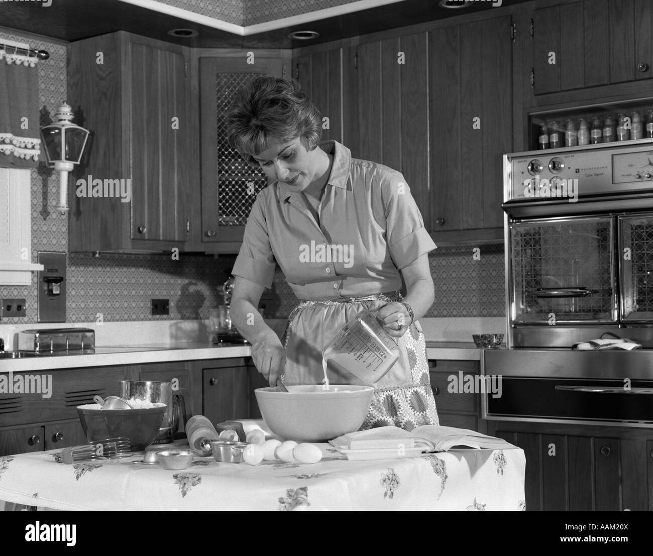 1960s WOMAN HOUSEHOLD PREPARE FOOD MIX KITCHEN Stock Photo