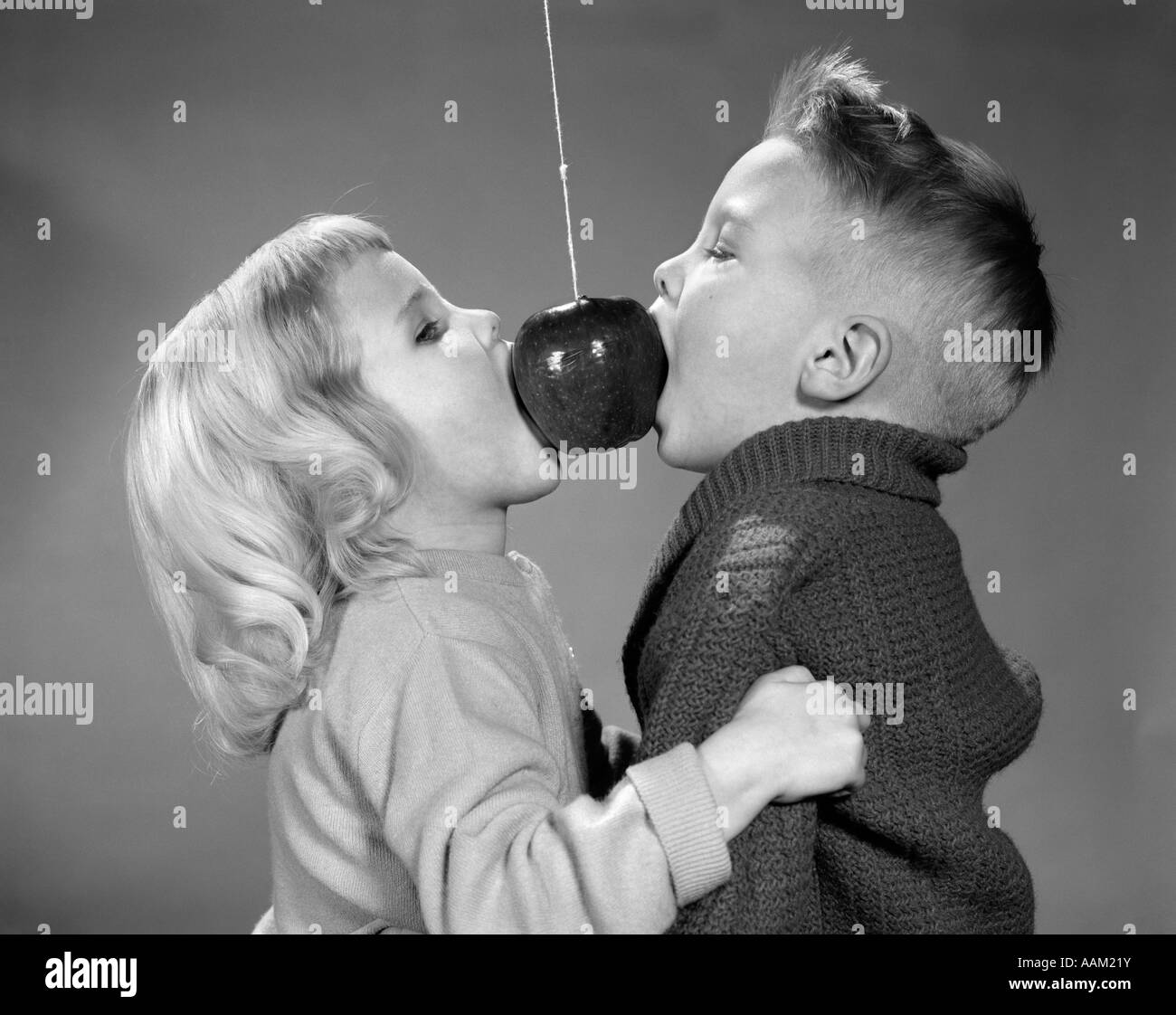 1950s 1960s BOY GIRL COUPLE BITING APPLE HANGING ON A STRING PARLOR PARTY GAME Stock Photo