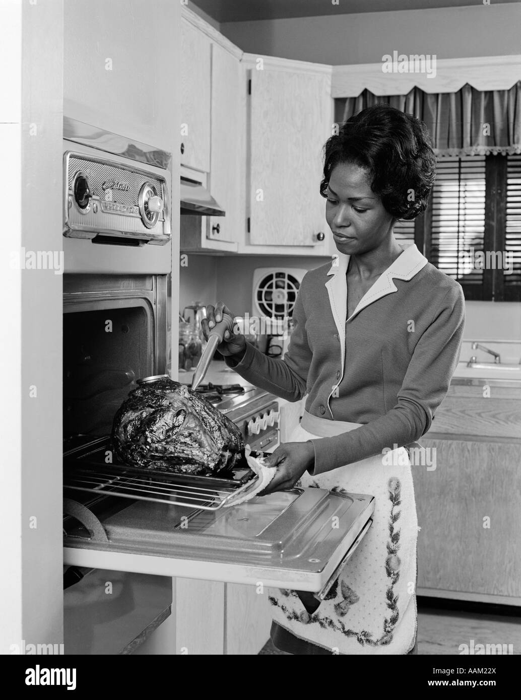 1970s BLACK WOMAN AFRICAN AMERICAN OVEN TURKEY THANKSGIVING Stock Photo