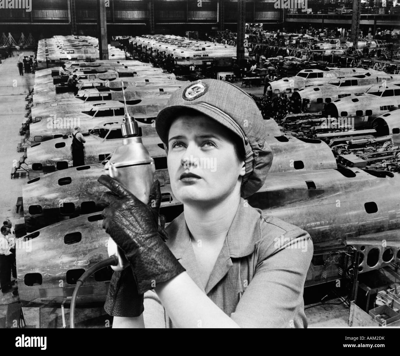 WOMAN ROSIE THE RIVETER SUPERIMPOSED OVER AIRPLANES IN FACTORY 1940s WARTIME WWII WORKER WORK Stock Photo