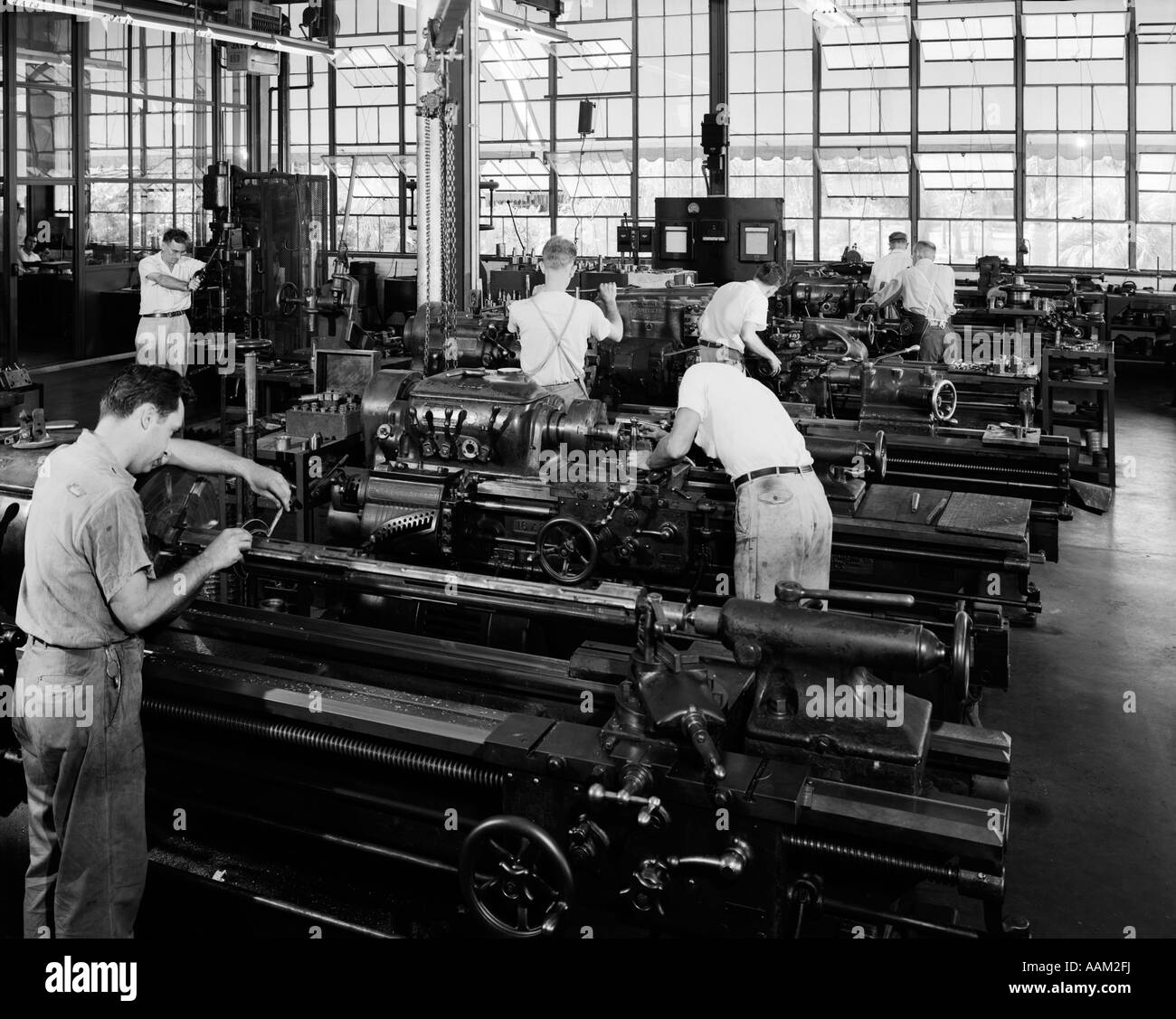 1930s GROUP OF MEN OPERATING LATHES IN LARGE FACTORY MACHINE SHOP Stock Photo