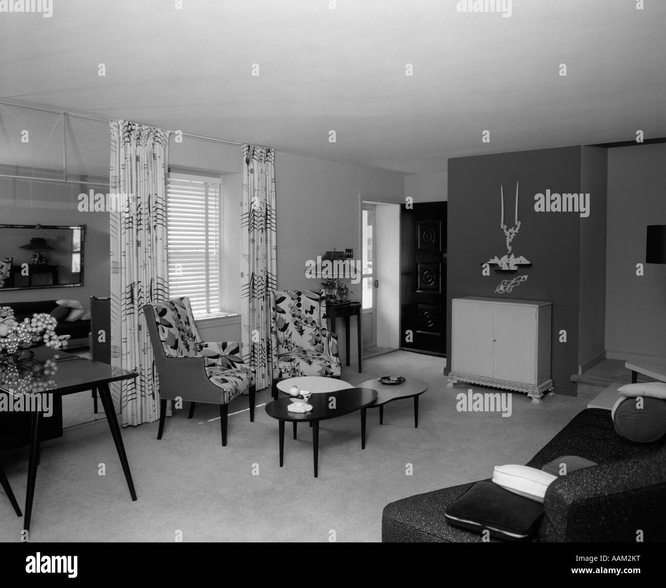1950s LIVING ROOM INTERIOR WITH KIDNEY-SHAPED COFFEE TABLES FLOOR-LENGTH CURTAINS & VENETIAN BLINDS Stock Photo