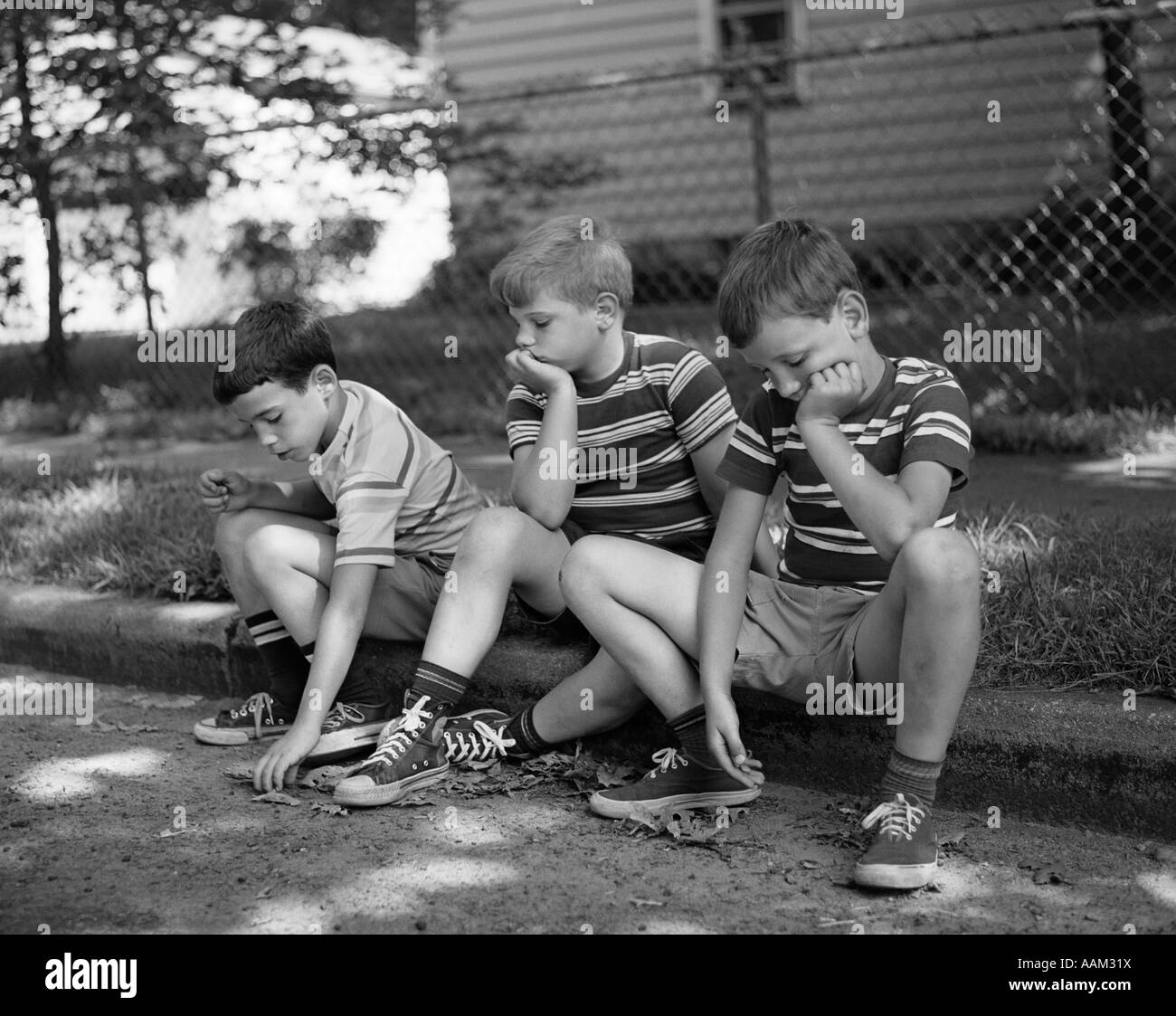 1970s THREE BORED BOYS SITTING ON CURB ALL WEARING STRIPED TEE SHIRTS SHORTS  AND SNEAKERS Stock Photo - Alamy