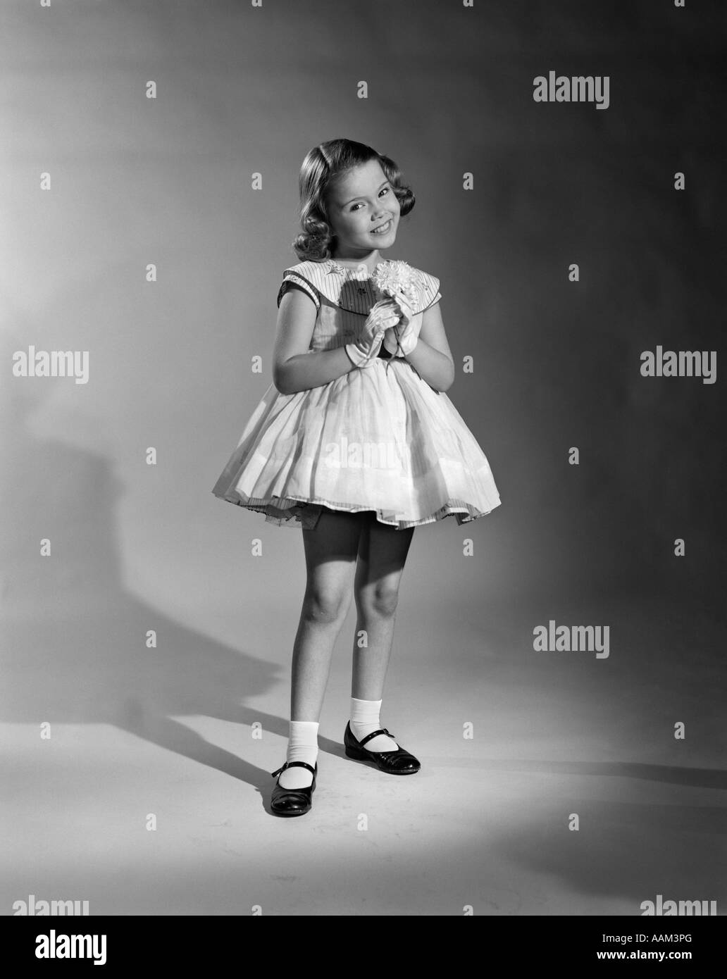 1950s PRETTY POSING GIRL SMILING FANCY DRESS WHITE GLOVES PATENT LEATHER SHOES FULL LENGTH SEAMLESS Stock Photo