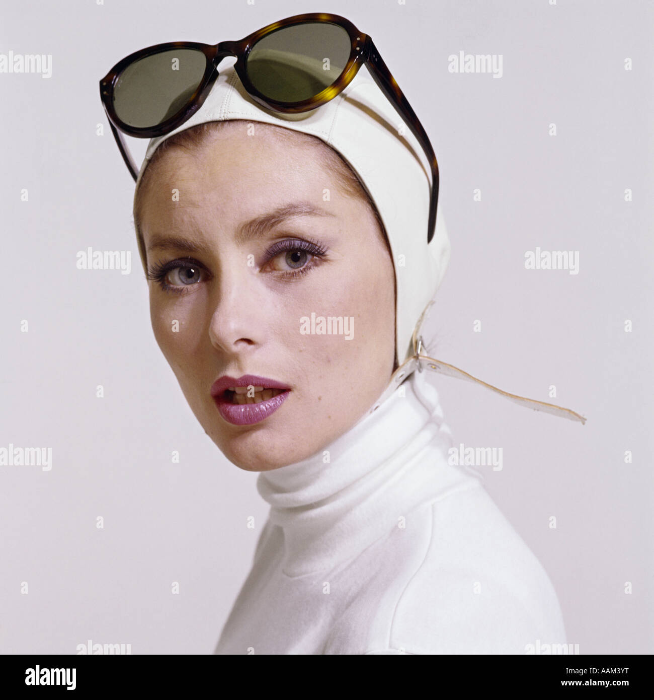 1970s PORTRAIT WOMAN WHITE TURTLE NECK WHITE AVIATOR HELMET HAT STRAP FASHION BEAUTY STYLE SUNGLASSES PUSH UP ON HEAD Stock Photo