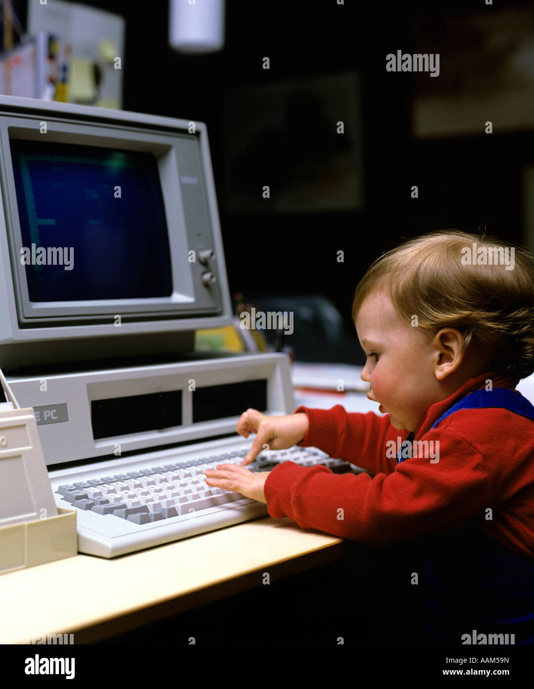 1980s YOUNG CHILD BOY GIRL PLAYING WITH EARLY IBM PC COMPUTER PRESSING KEY ON KEYBOARD Stock Photo