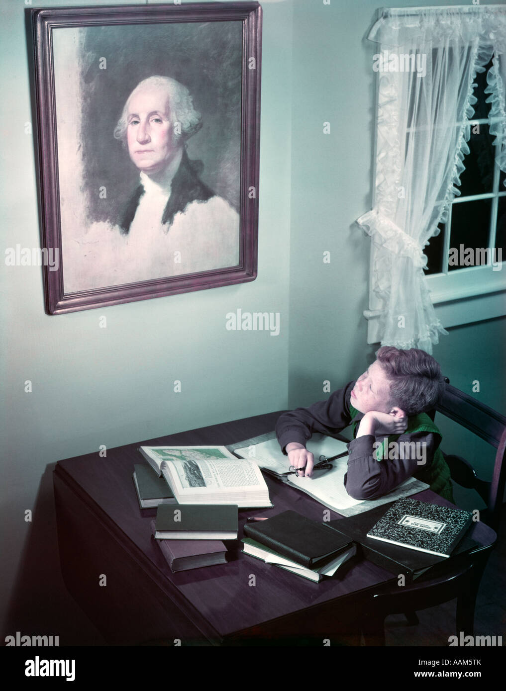 1940s 1950s BOY AT DESK READING STUDYING LOOK UP AT PAINTING ON WALL OF GEORGE WASHINGTON HISTORY PATRIOTISM Stock Photo