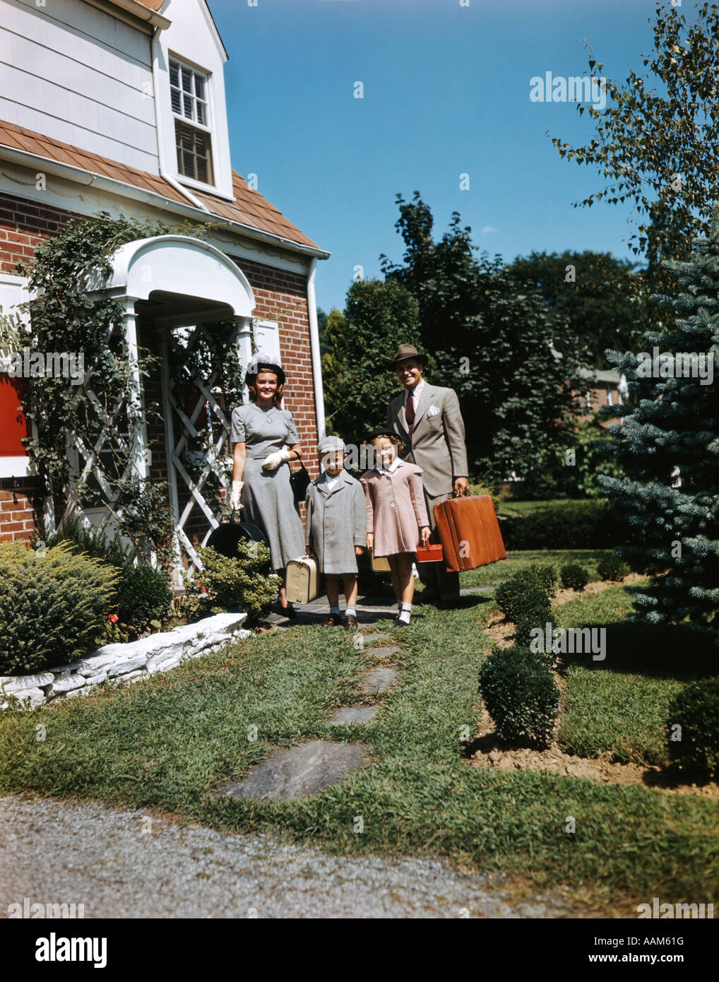 FAMILY WITH LUGGAGE IN FRONT OF HOME Stock Photo