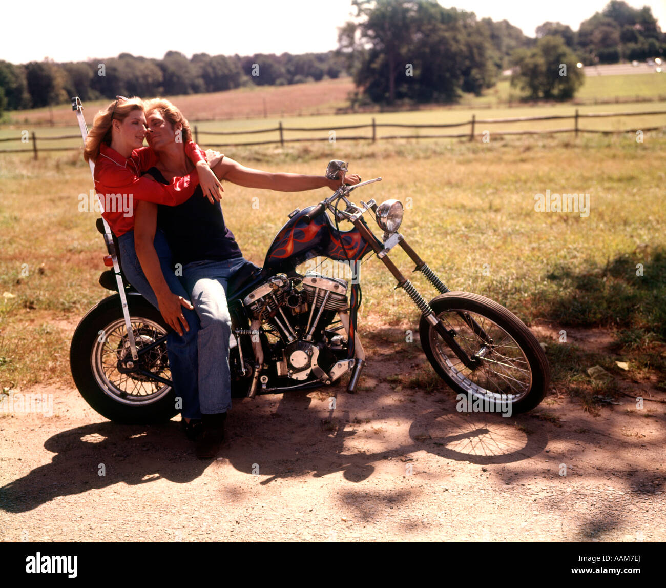 1970 1970s COUPLE MAN WOMAN HUGGING ROMANTIC SITTING ON CHOPPER MOTORCYCLE BIKE MOTORBIKE MOTOCYCLES BIKES Stock Photo