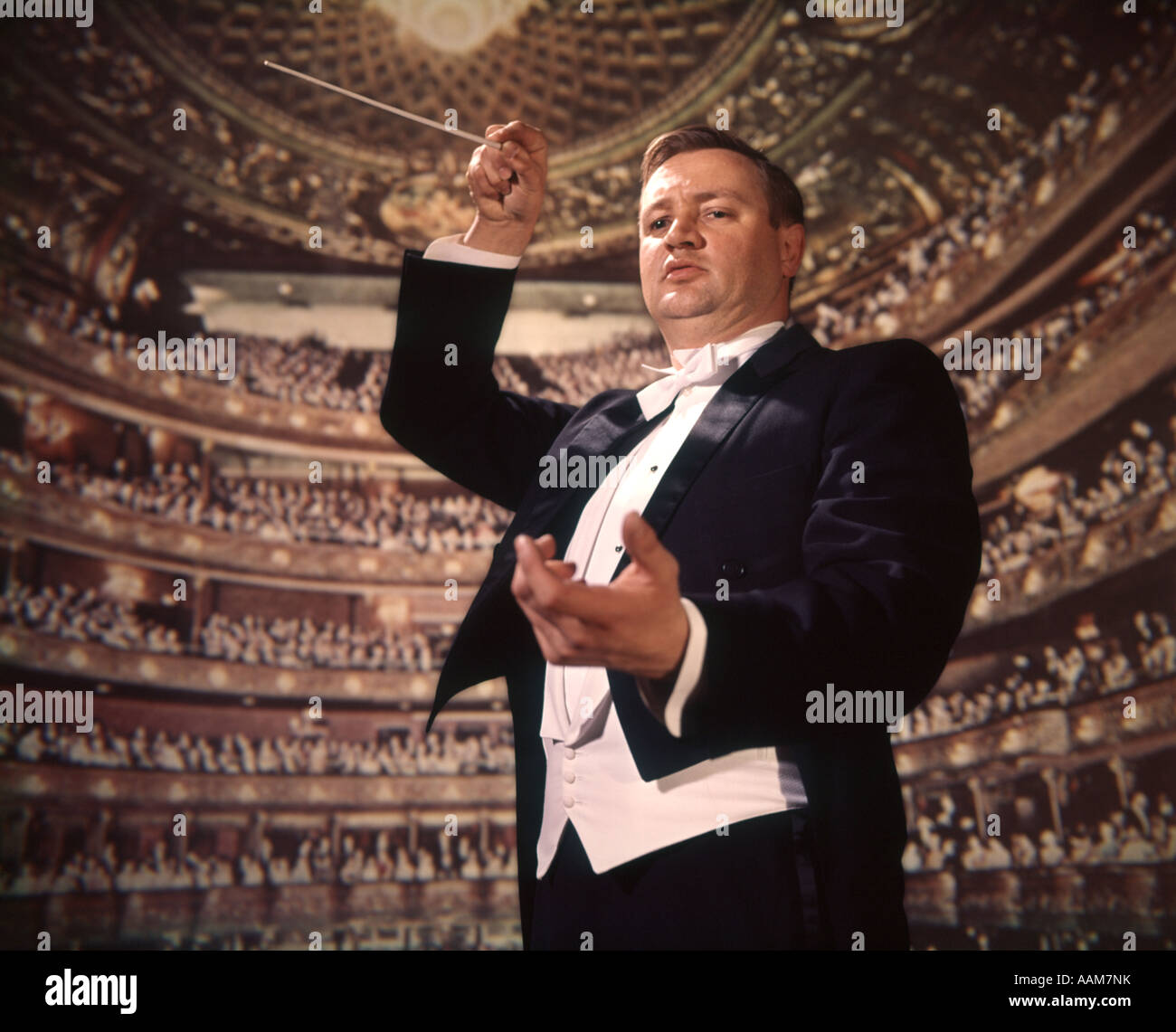 1960s 1970s 1980s MAN ORCHESTRA LEADER BATON CONDUCTOR CONDUCTING AUDIENCE BACKGROUND Stock