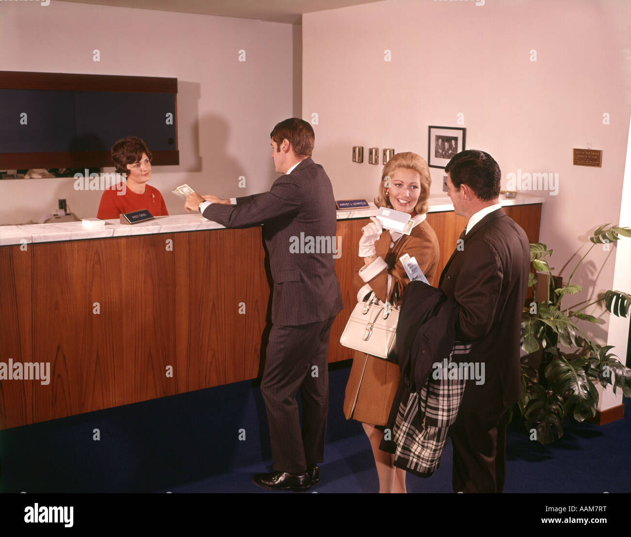 1960 1960s THREE PEOPLE IN LINE WAITING FOR BANK TELLER CASHIER Stock Photo