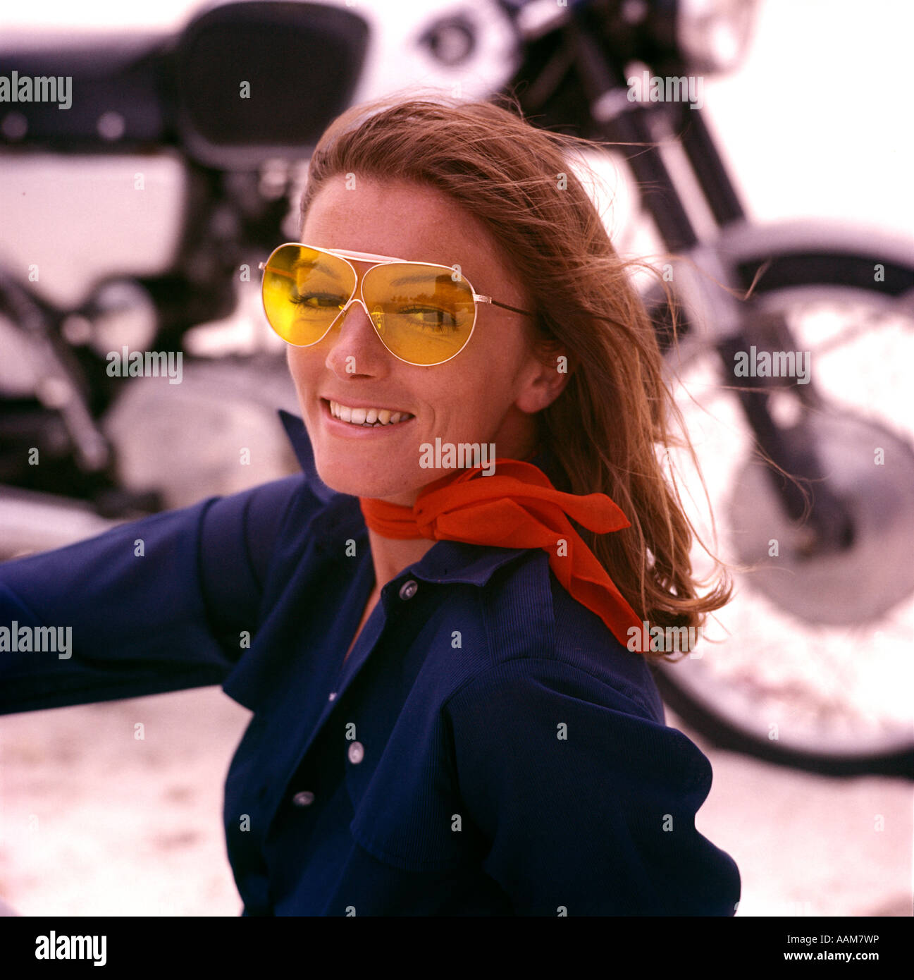 WOMAN MOTORCYCLIST SMILING YELLOW SUNGLASSES RED SCARF MOD 1970s 1970 RETRO Stock Photo
