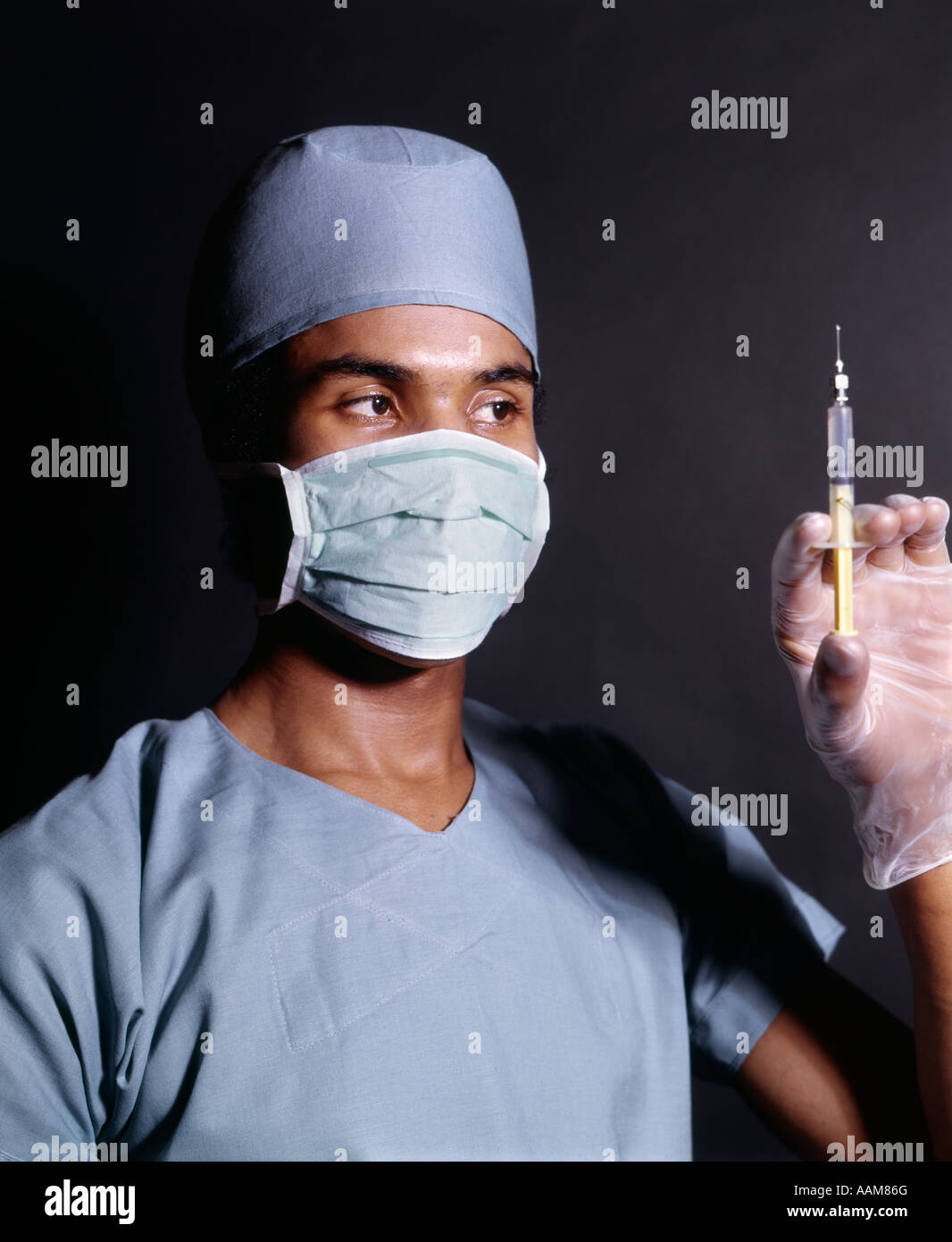 1970s AFRICAN-AMERICAN MAN DOCTOR NURSE SURGICAL MASK GOWN GLOVES HOLDING HYPODERMIC SYRINGE NEEDLE INJECTION SHOT Stock Photo