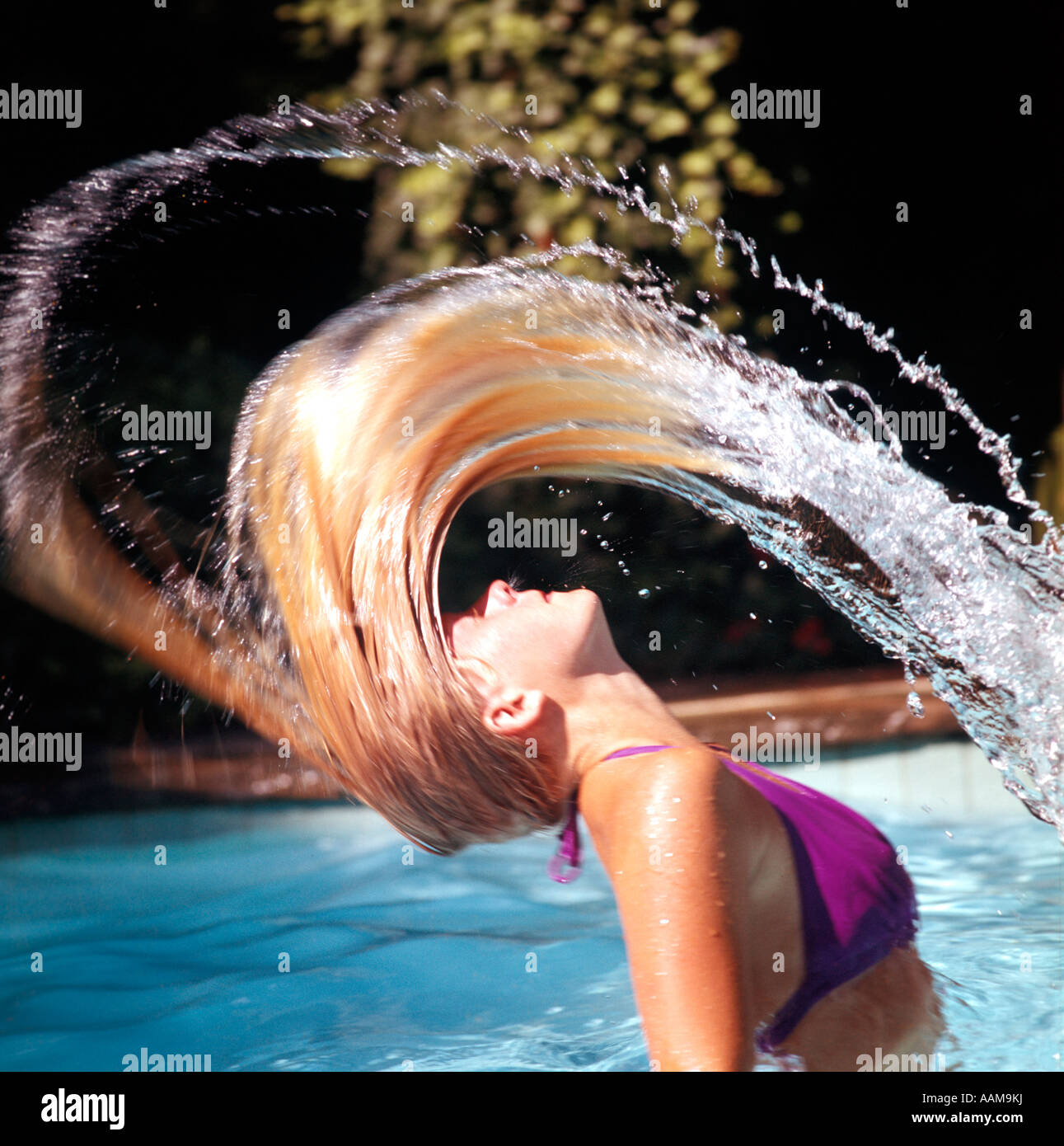 1970 1970s BLOND WOMAN PINK BIKINI JUMP UP IN POOL WHIPPING BACK LONG WET HAIR STROBE RRR RETRO BLONDE Stock Photo